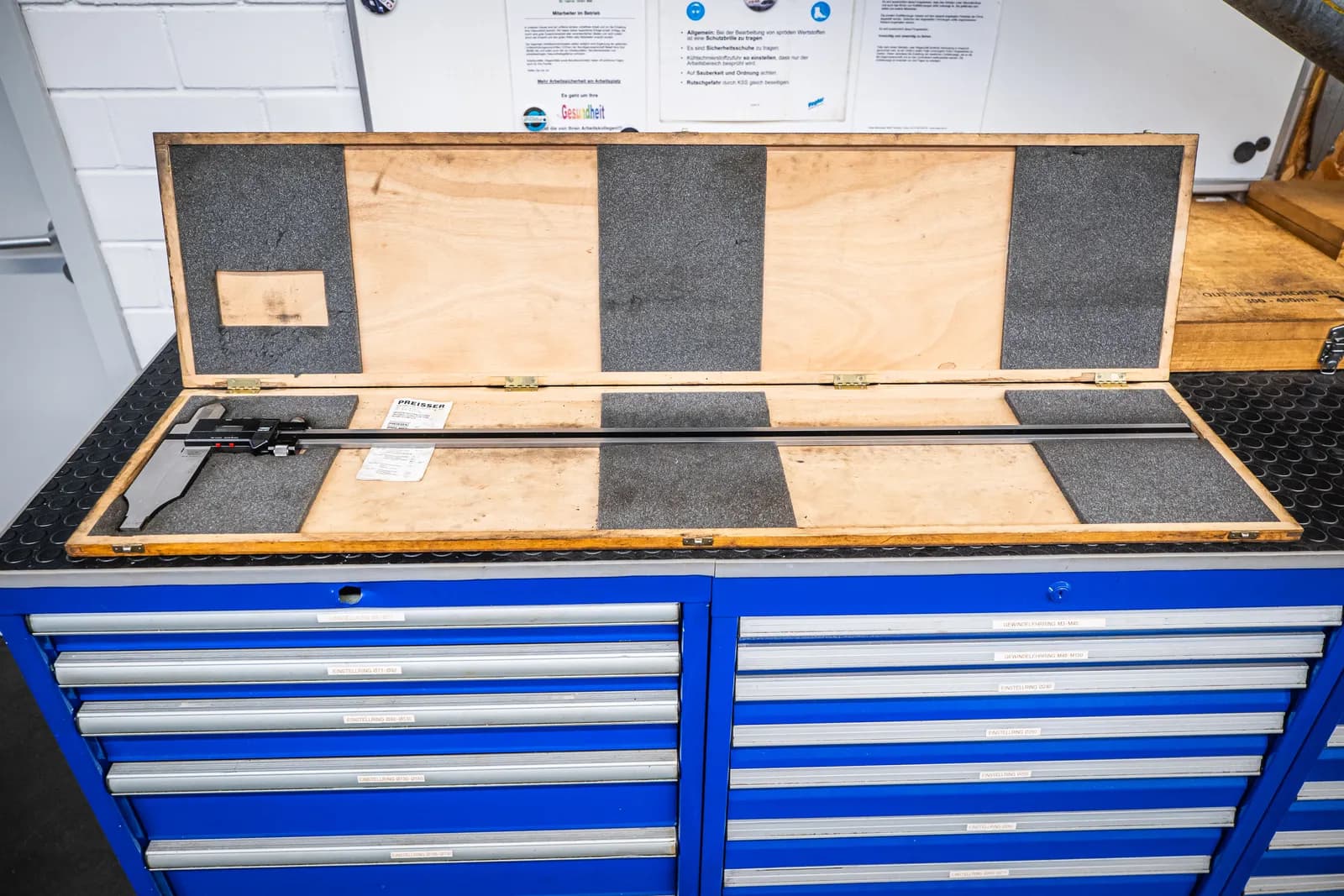 Großer Messschieber im Holzkasten auf Schubladenschrank